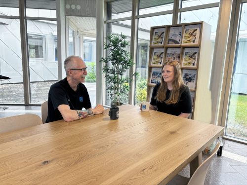 Larry och Matilda samtalar vid ett bord.
